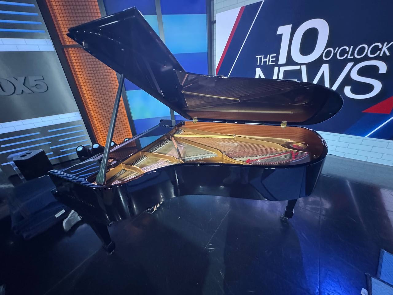 Grand piano with its lid open on a television news set